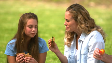 madre y su hija comiendo un sándwich juntos