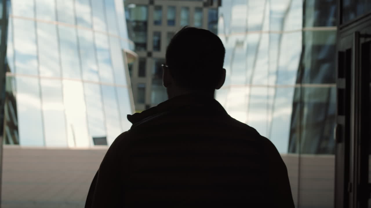 Unrecognizable Man Walking Past Glass Buildings