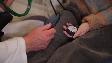 the doctor examines the girl, measuring blood pressure with a clinical tonometer. family doctor.