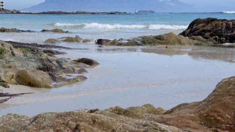 inclínate desde una roca en la playa para revelar la montaña de la mesa y un barco en la distancia