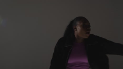 retrato de estudio de una mujer joven bailando con iluminación baja contra un fondo gris 9