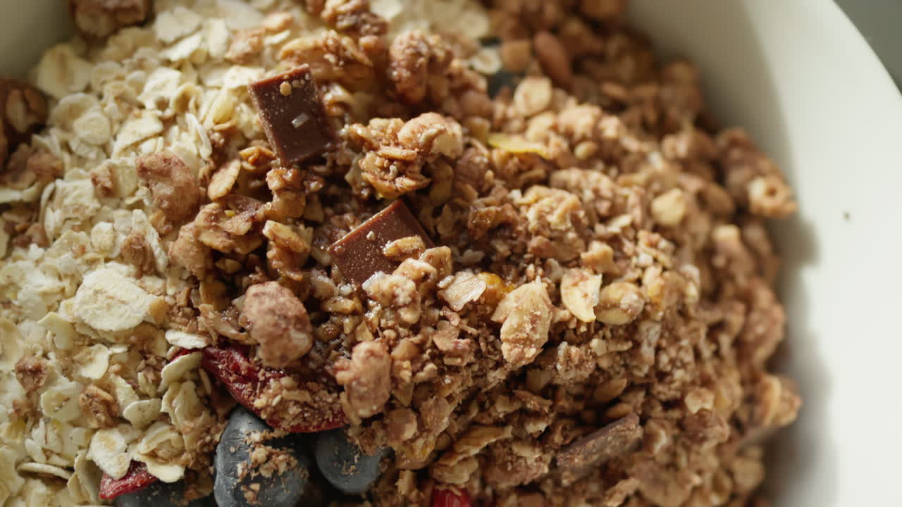 primer plano de un cuenco de desayuno con granola, chocolate y bayas en una mesa