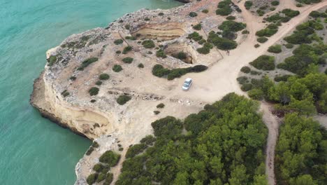 playa de fontainhas en el sur de portugal con furgoneta estacionada en la parte superior del mar cuevas talladas, aproximación aérea inclinada hacia abajo