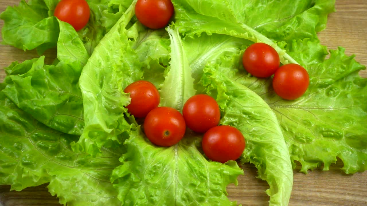 Falling of tomatoes on lettuce leaves. Slow motion