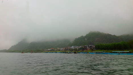 misty mountains seen from the boat cruising in phong nha river in vietnam. - pov shot