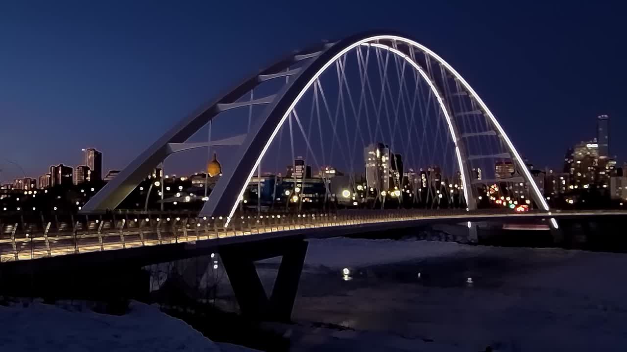 4k 보케 흐림 시간 경과 루프 일몰 겨울 밤, 스카이라인 고층 건물 호텔 콘도 4-4가 있는 얼어붙은 북쪽 서스캐처원 강이 있는 흰색 현대 월터 데일 나비 넥타이 다리의 반사