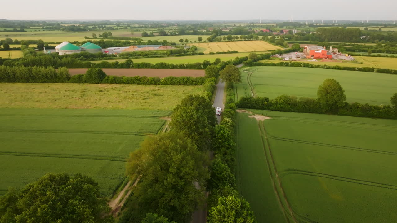 Aerial view of a motorhome parking in middle of blooming farmlands, summer sunset