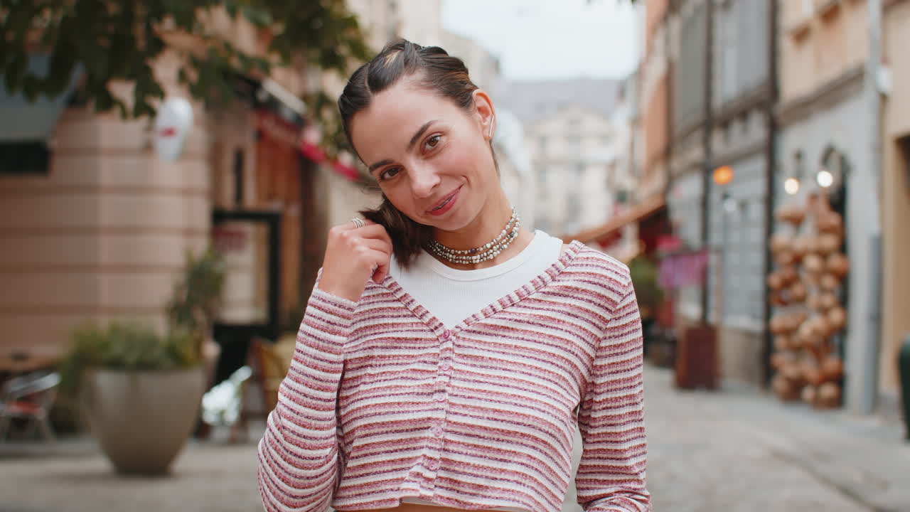 Happy attractive young woman girl on urban city street looking shy at camera and smiling flirting