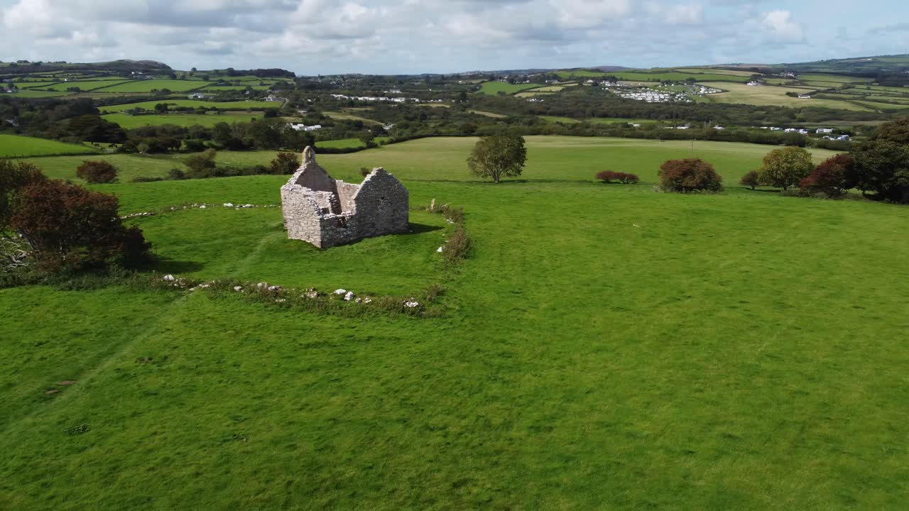 Establishing aerial view circling Capel Lligwy ruined chapel on Anglesey island coastline, North Wales