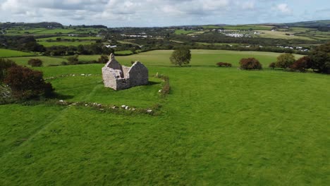 establishing aerial view circling capel lligwy ruined chapel on anglesey island coastline, north wales