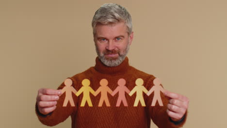 Man showing multiracial different skin color human shape cut out of paper against racism community