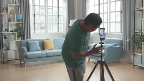 asian man blogger shoots video content for social networks by smartphone camera, magician with playing cards