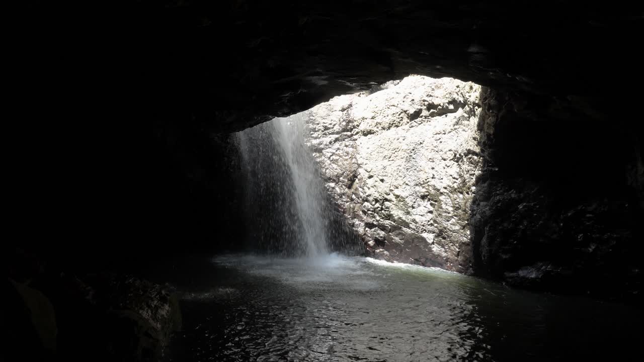 cascadas de agua a través del techo de una cueva submarina del bosque de la era jurásica iluminada por rayos de luz solar