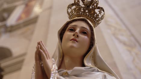 close up of crowned virgin mary statue with rosary inside bom jesus church in braga portugal
