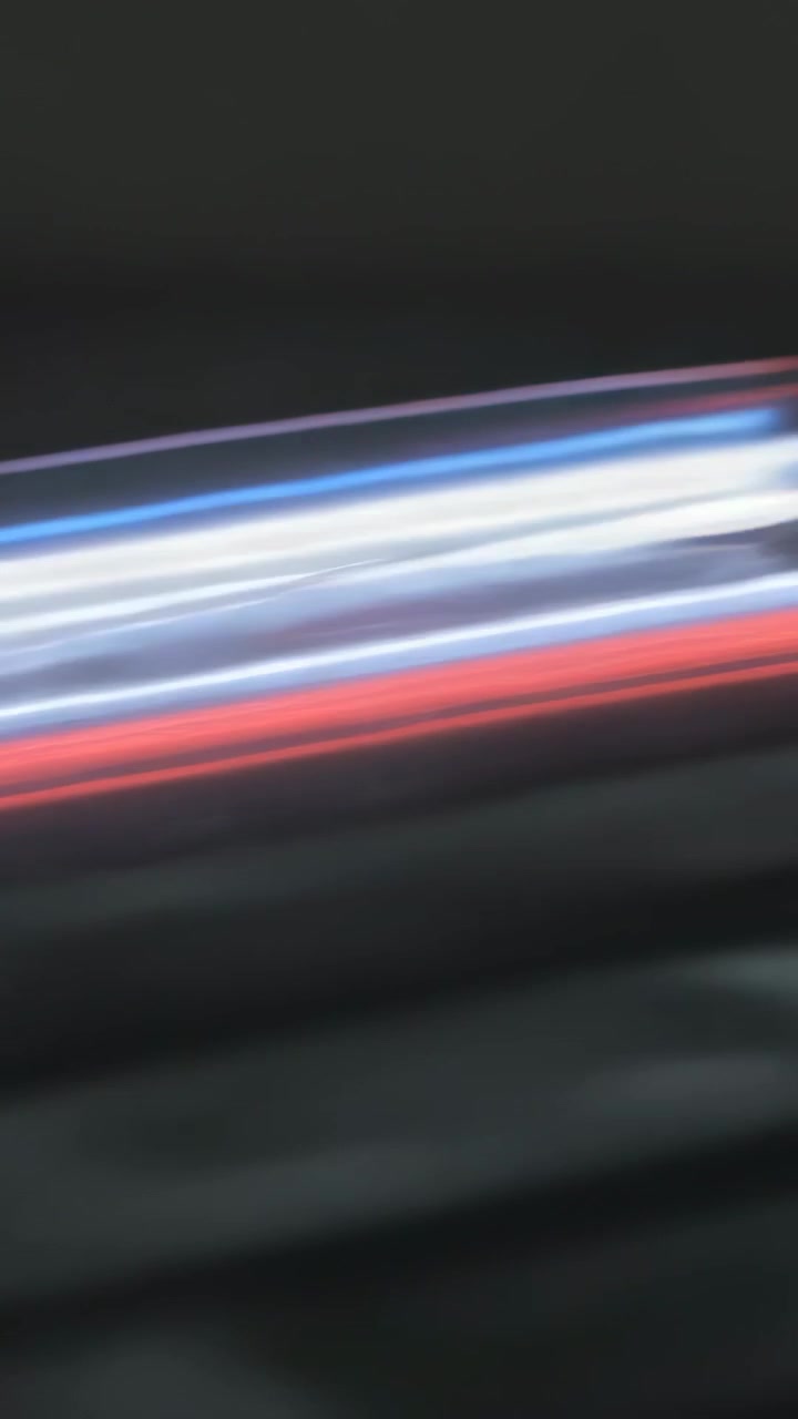 Vertical video: Recording camera moving along night pavement showing motion blur in red white bands
