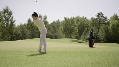 Asian-mature-woman-practicing-golf-on-sunny-day