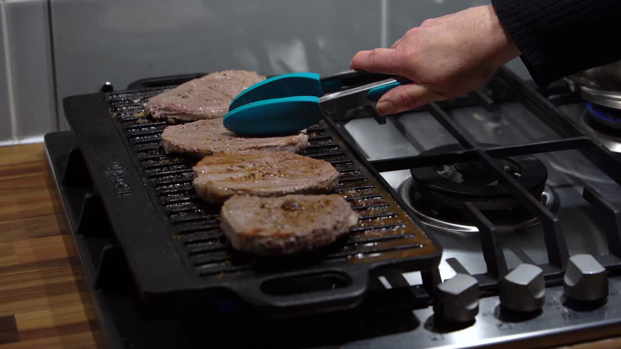 Pressing and flipping steaks cooked on electric griddle