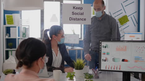 business people with medical face masks sitting in new normal company office