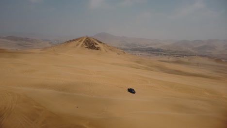 AERIAL---Off-road-4x4-truck-tracks-in-Ica-desert-sand-dunes,-Peru,-spinning-shot