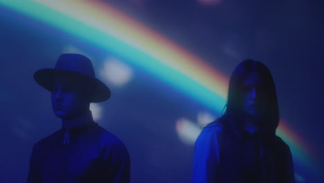 couple in creative costumes in dark studio with rainbow light