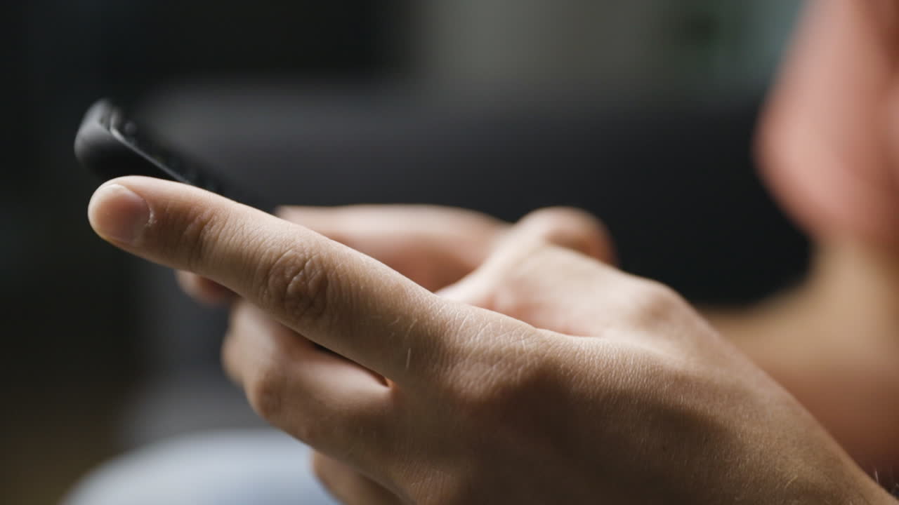 Close-up from side of male hands typing on smartphone, shallow DOF