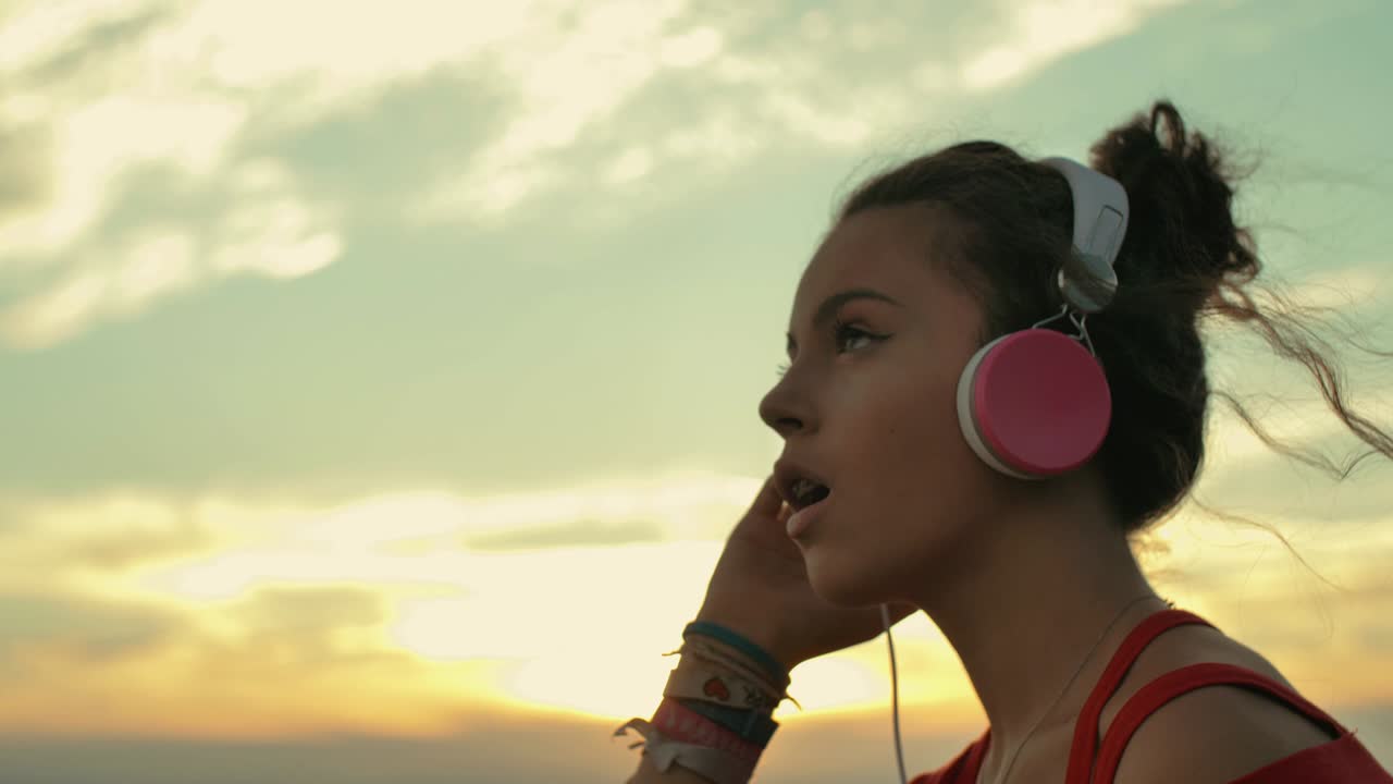 una adolescente con auriculares escuchando música en la playa. filmada a cámara lenta