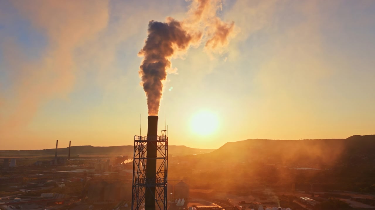 Alba su una fabbrica con fumo che sale nel cielo in un'area industriale