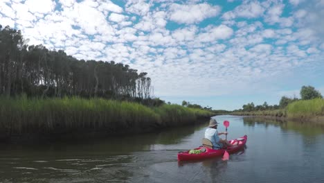 Slow-motion-shot-following-a-man-paddling-down-a-river-in-a-red-kayak