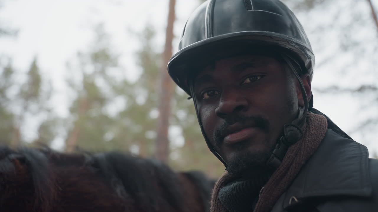 jinete silencioso en bosques tranquilos, figura ecuestre serena con casco en un entorno invernal apagado, jinete sereno con equipo de protección mirando fijamente en un bosque tranquilo durante el invierno