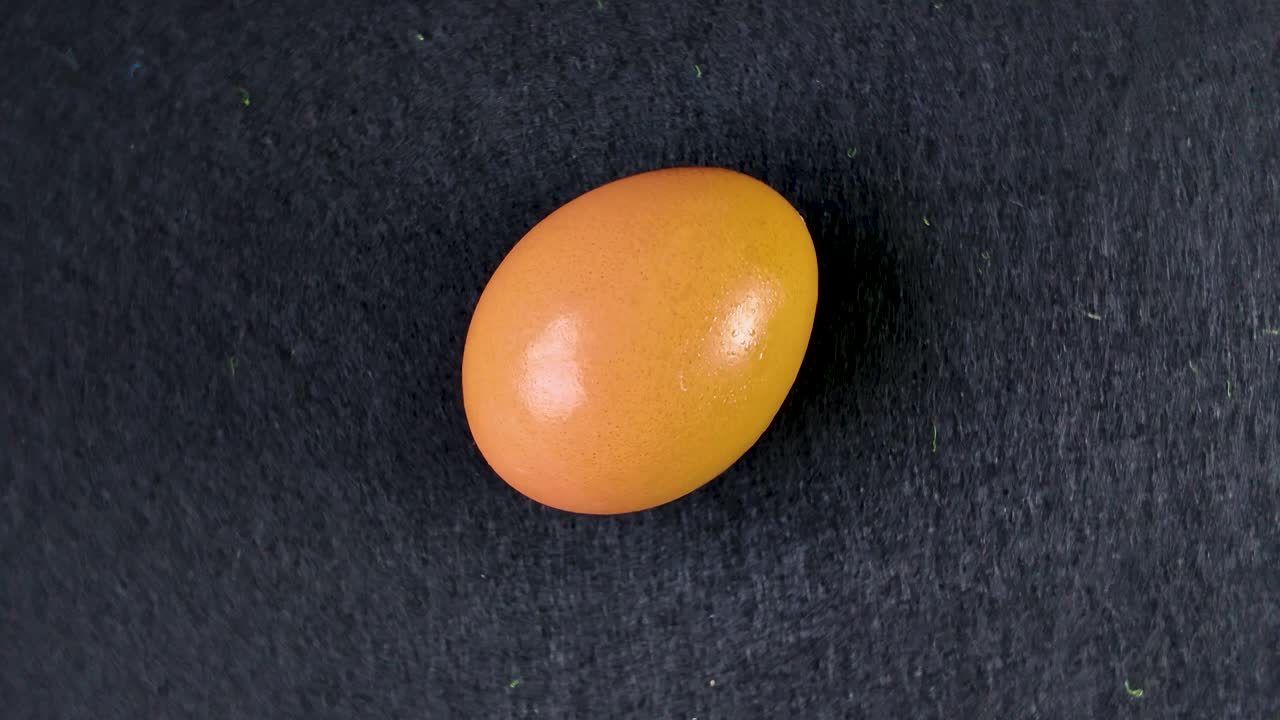 Chicken egg rotating clockwise on a black slate surface, creating a mesmerizing culinary visual