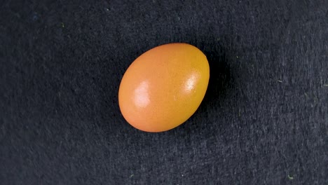 chicken egg rotating clockwise on a black slate surface, creating a mesmerizing culinary visual