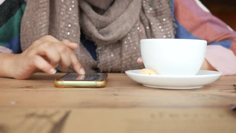Women-hand-using-smart-phone-and-drinking-coffee-in-a-cafe-,