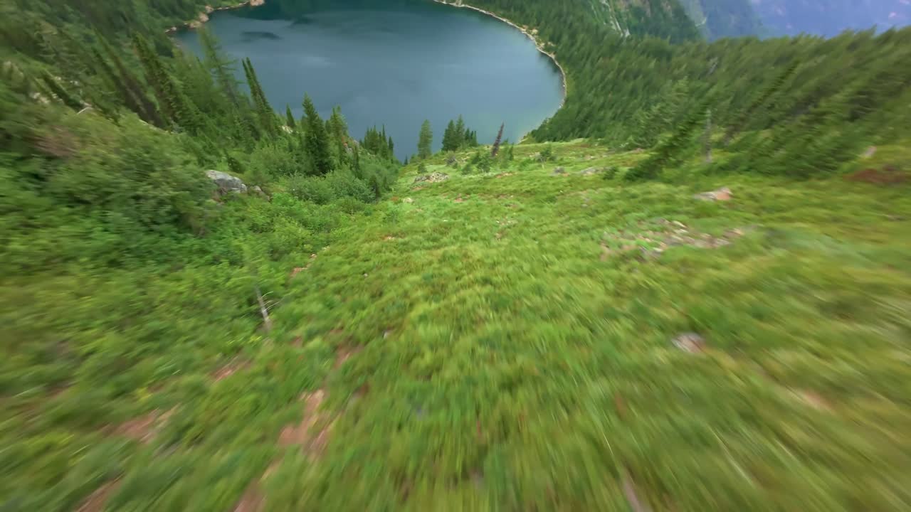 A DJI Avata 2 first person view (FPV) drone diving or mountain surfing down a gully dangerously close to trees to Lower and Upper Stevens Lake on the border of Idaho and Montana near Coeur D'Alene