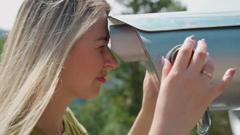 smiling woman turns wheel looking in binoculars at resort