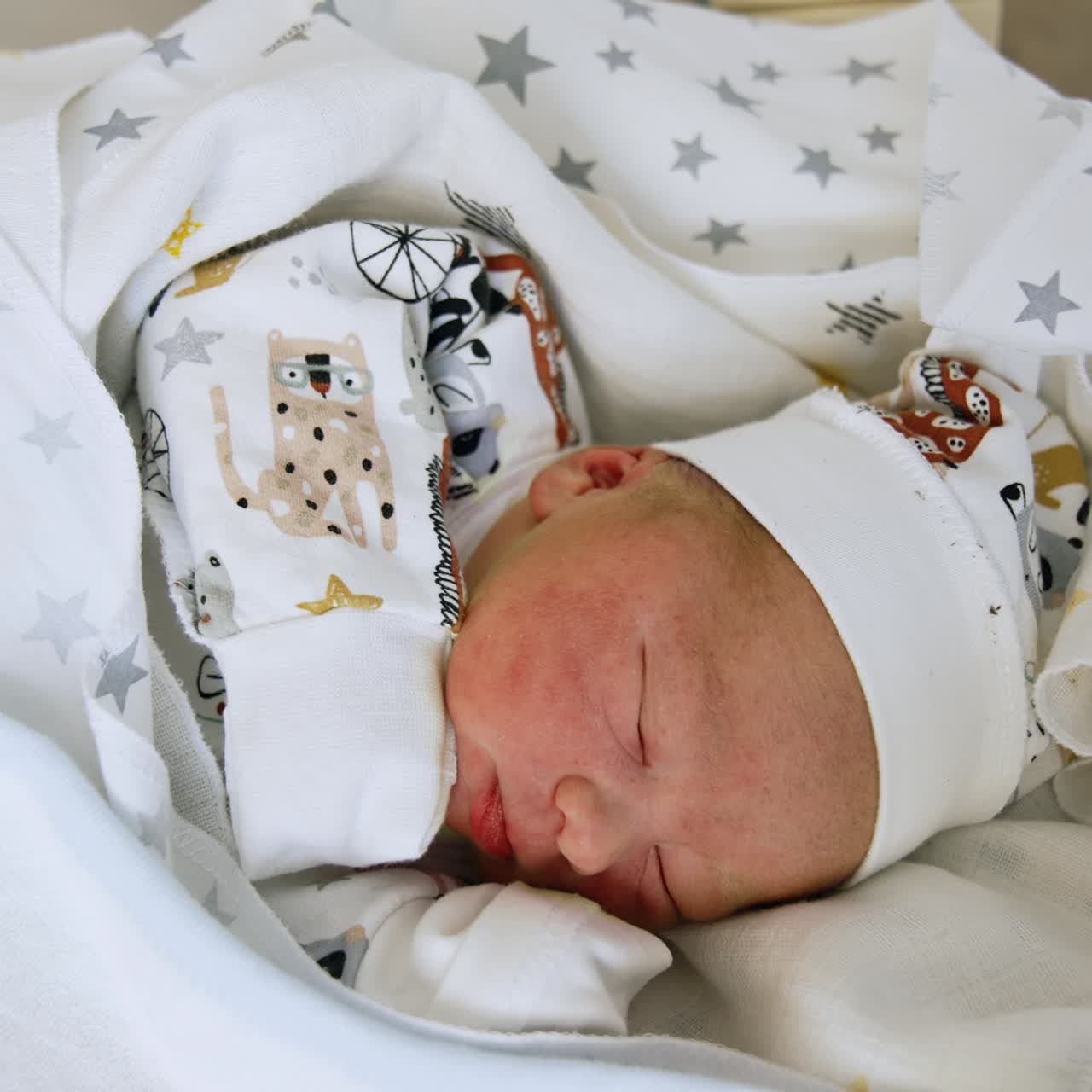 Neonato caucasico in miniatura con cappello e maglietta. Il bambino dorme tra le coperte e apre la bocca