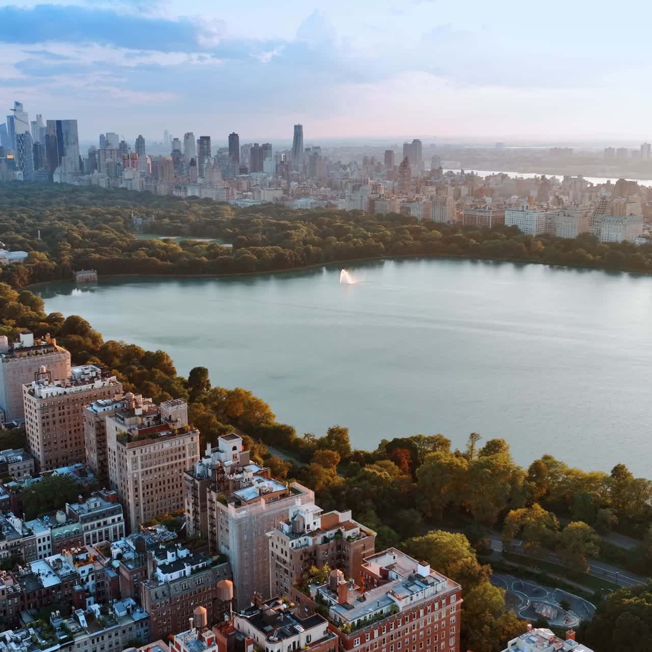 Superficie liscia del bacino idrico a Central Park, New York. Splendido scenario della meravigliosa città e area verde al tramonto