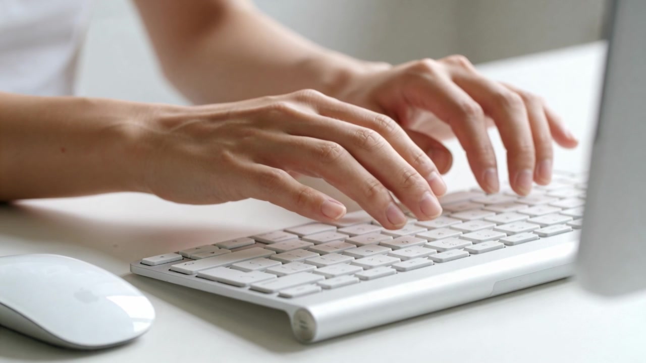 Starting typing, hands wearing short sleeves pressing keys on white keyboard at home desk for work