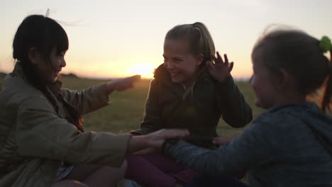 portrait of little girls playing games sitting in park at sunset enjoying fun games together