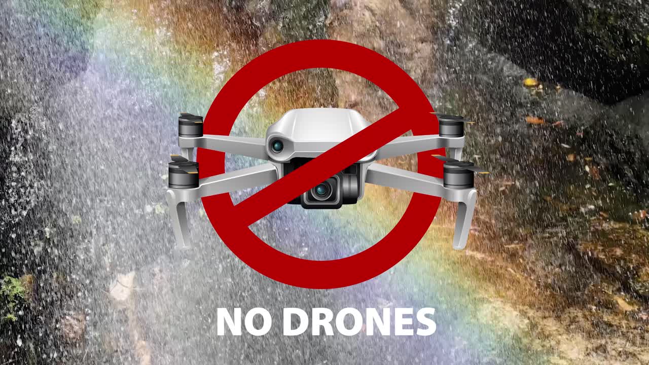 Aerial view of a waterfall with a rainbow, highlighting a no-drone zone. Vibrant colors and natural beauty emphasized