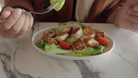 woman eating a delicious salad with cheese, tomatoes and walnuts