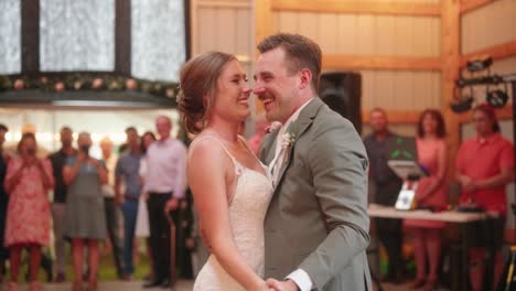 bride and groom enjoy their first dance together happily while surrounded by guests