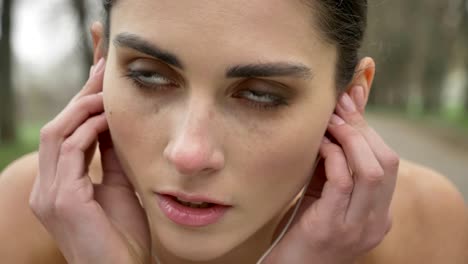 joven motivada está usando auriculares y corriendo en el parque en verano, estilo de vida saludable, concepción deportiva