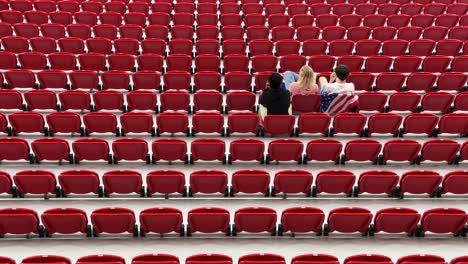 a couple sit in the red seats of stadium hopeful and excited to watch the football match between usa iran in doha qatar makes red pattern shapes focused perspective wide view landscape interior design