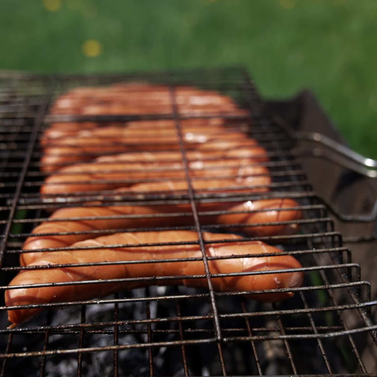 Man putting sausages on the grill. Grilled fresh meat sausages on an open air. Ruddy sausages are fried on charcoal. Close-up