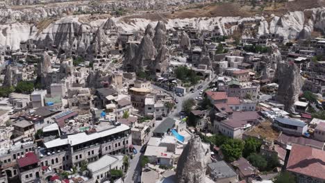 drone descends over rock spires with homes built along roads in valleys on edge of cappadocia turkey