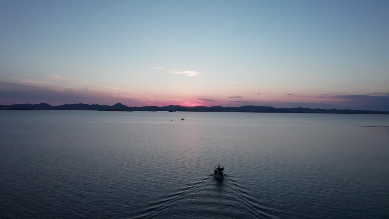 보트가 바다로 달려가는 분홍색과 파란색의 시간 색조는 새벽에 지평선에 빛을 니다.