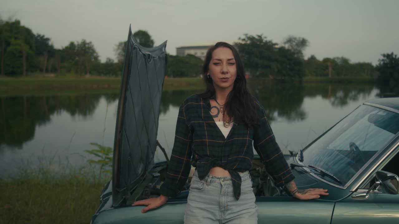 Donna con un'auto d'epoca in panne vicino al lago