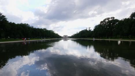 Blick-Vom-Wasser-Auf-Die-Vorderstufen-Des-Lincoln-Memorial,-Aufgenommen-Vom-Reflexionsteich-Mit-Menschen-Im-Vordergrund