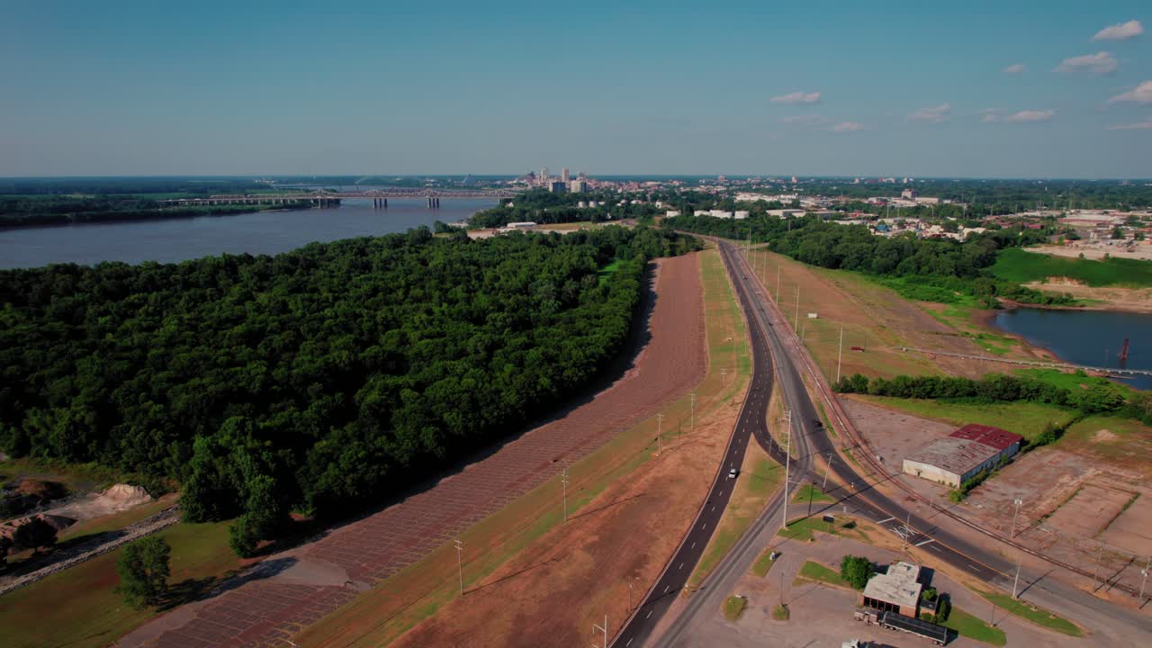 Dramatic rising drone shot over Mississippi River forests revealing Memphis Tennessee urban skyline with bridges infrastructure