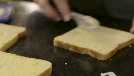 Mujer-Joven-Ocupada-Untando-Pan-Con-Mantequilla-Para-Hacer-Sándwiches-A-La-Barbacoa-Para-El-Almuerzo